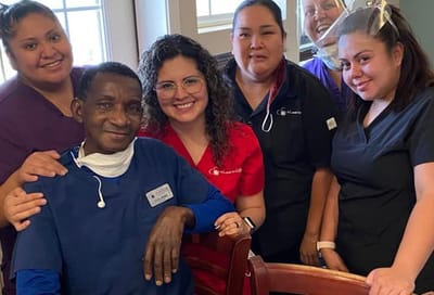 Staff posing with a resident in a facility interior