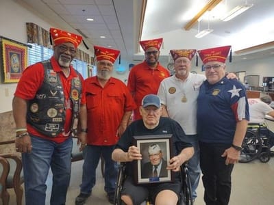 Group of veterans posing with a framed portrait in a common area