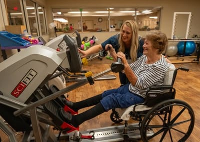 A staff member assisting a resident with fitness equipment