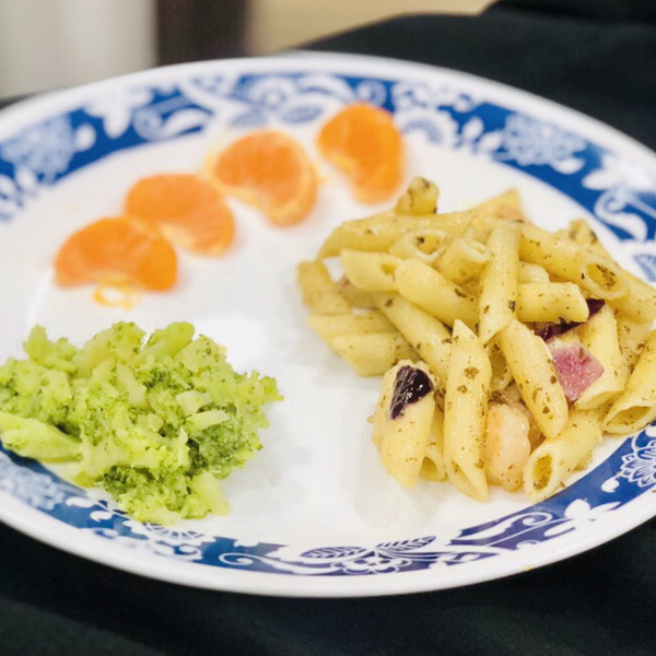 A plated meal with pasta, broccoli, and fruit