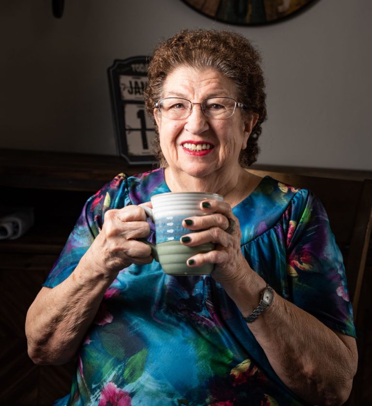 A resident enjoying a cup of tea in a colorful top