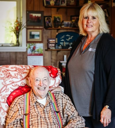 A resident smiling with a staff member in a cozy room