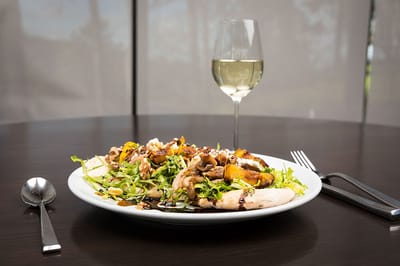 A gourmet salad with chicken and a glass of white wine