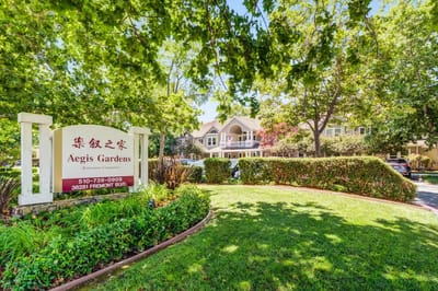 Exterior view of Aegis Gardens with sign and landscaping