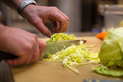 Hands chopping cabbage in kitchen
