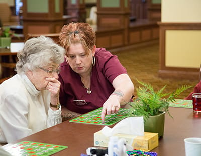 Resident playing bingo with staff in an activity room
