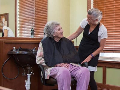 Resident enjoying a hair salon service with a staff member