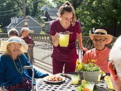 Residents enjoying refreshments outdoors with staff