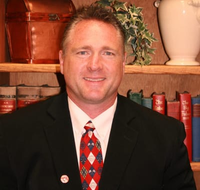 Man in a suit with bookshelves in the background