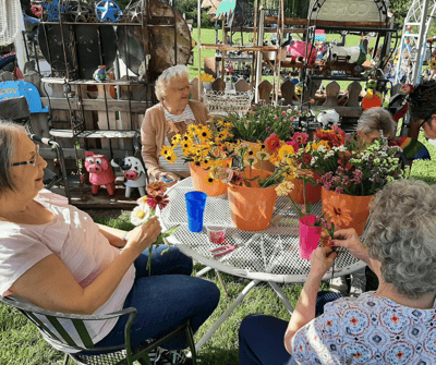 Residents engaging in flower arrangement outdoors.