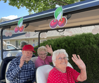 Residents enjoying a golf cart ride and waving