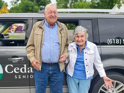 Two residents posing by the facility vehicle