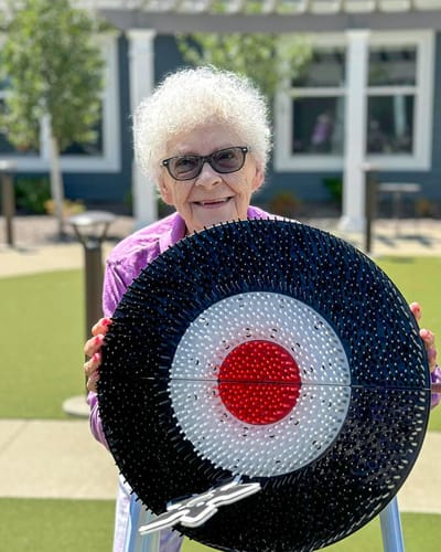 Resident outdoors holding a colorful game board