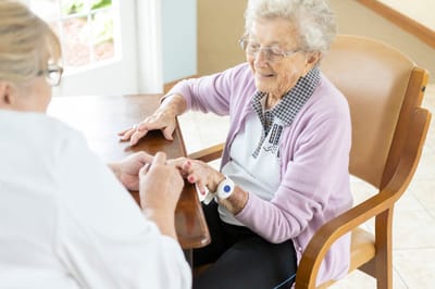 A caregiver interacting with a senior resident at a table