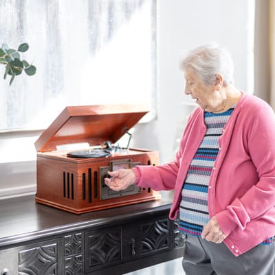 An elderly woman using a vintage record player