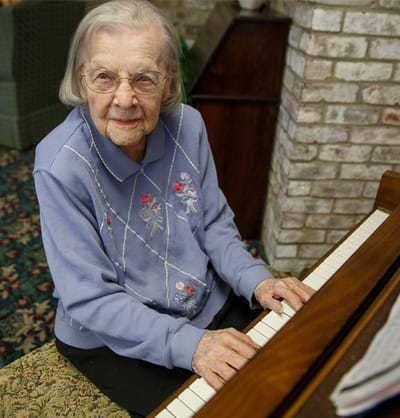 Resident playing piano in a cozy interior setting