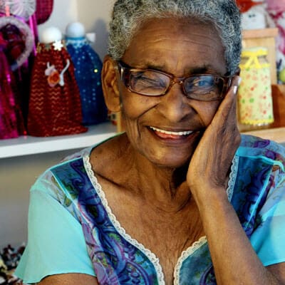 A smiling senior woman sitting with decorative items in the background