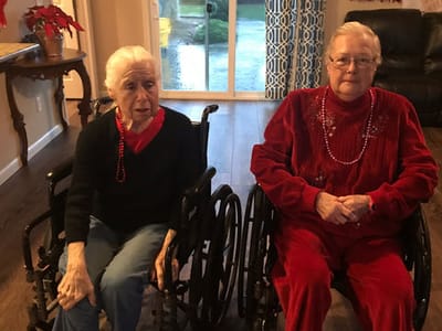 Two residents in wheelchairs in a cozy common area