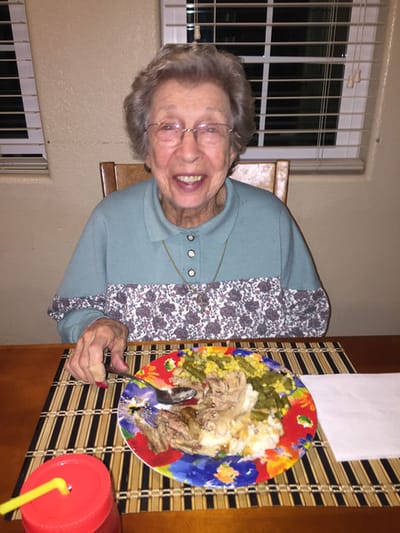 An elderly woman enjoying a meal with a smile