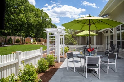 Outdoor patio with seating and umbrellas in a green space
