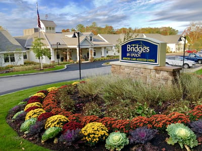 Facility sign in front of the building with flower beds.