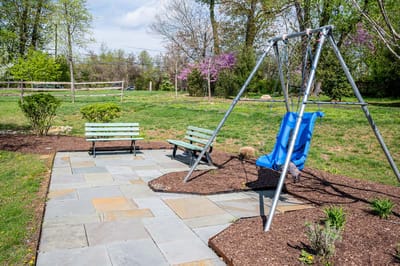Outdoor swing set and benches in a garden area