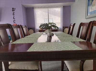 Dining table set with green placemats and a flower pot