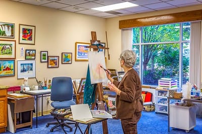Resident painting in a bright activity room