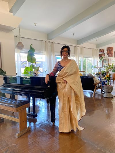 Resident in traditional attire by a piano in the common area