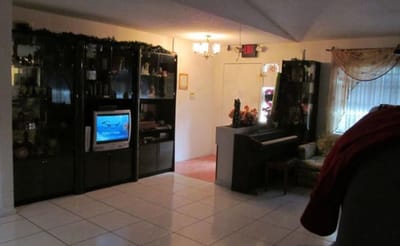 Common area with a television and piano in an assisted living facility
