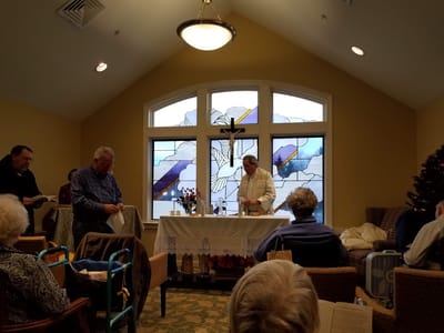 Residents participating in a religious service with a stained glass window