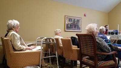 Residents sitting in a common area listening to a speaker