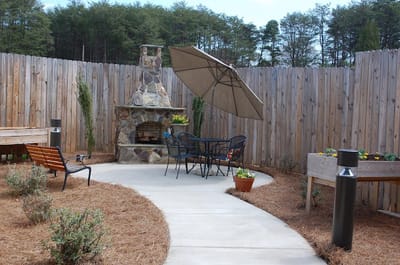 Outdoor seating area with a stone fireplace and garden beds
