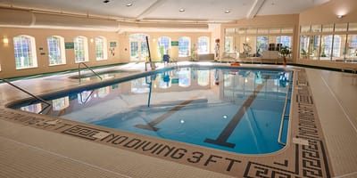 Indoor pool area with natural light and seating