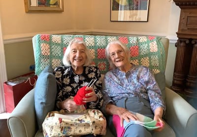 Two residents knitting in a cozy common area