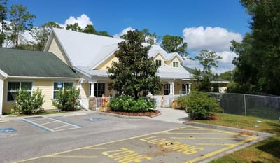 Exterior view of Magnolia Manor with trees and parking lot