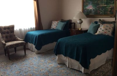 A cozy resident room with two beds and a decorative chair