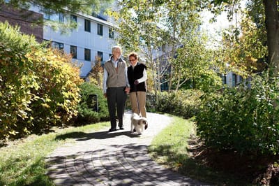 Residents walking on a garden path with a dog
