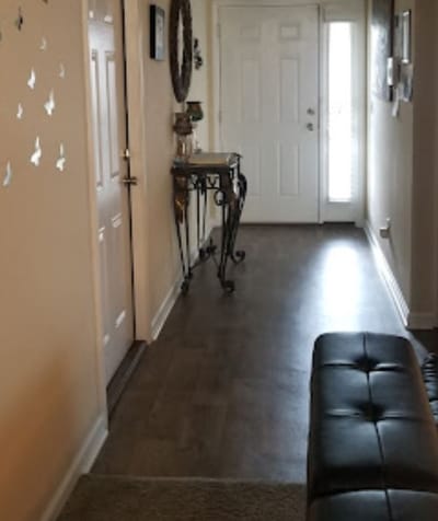 A view of the hallway inside Eternally Rich Assisted Living Facility, showing a console table and front door.