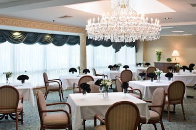 Elegant dining room with chandelier and tables set for meals