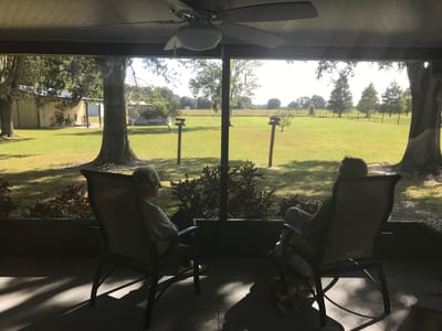 Two residents enjoying the view from a screened porch