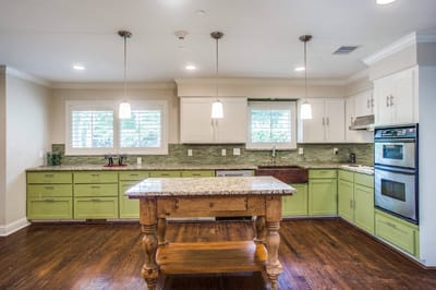 Bright and modern kitchen with green cabinets and granite countertop