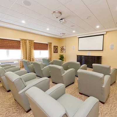 An interior activity room with seating and a projection screen