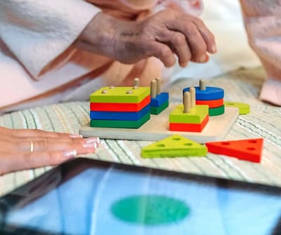 An elderly person engaging with colorful activity blocks