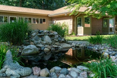 Exterior view of the facility with a pond and garden