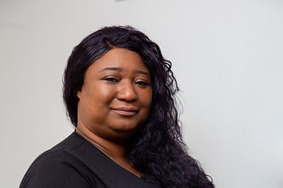 Staff member smiling with textured hair.
