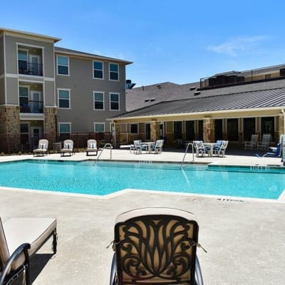 Outdoor pool area with lounge chairs and building backdrop
