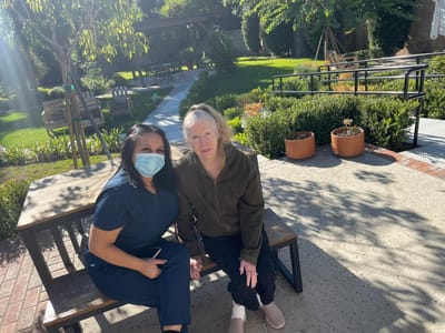 Staff member poses with a resident in the garden area