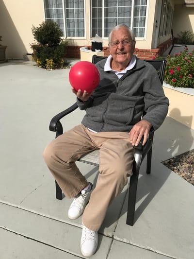 A resident holding a red ball in an outdoor space