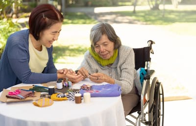 Resident and volunteer engaged in a craft activity outdoors